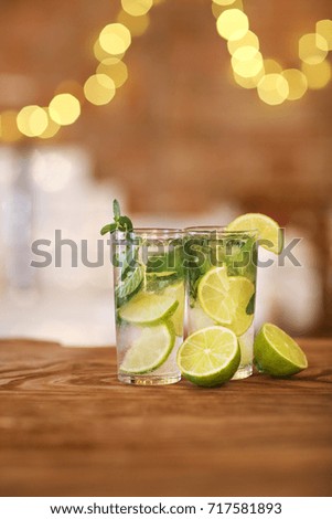 Two cocktail glasses with lime and mint on wooden bar counter