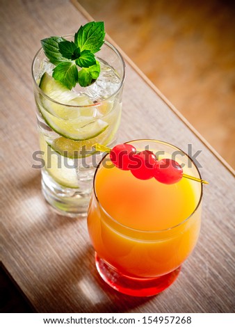 Two cocktails, tequila sunrise and gin and tonic