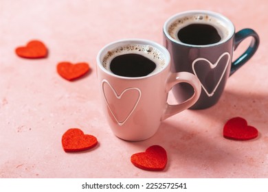 Two coffee cups with heart in pink and black colors standing for female and male gender on pink table with red hearts around, top view. Valentines Day holiday - Powered by Shutterstock