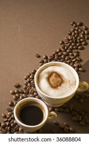 Two coffee cups with hot espresso and cappuccino over brown background