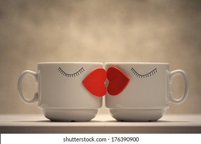 Two coffee cups with red hearts as a kissing lips