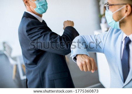Two colleagues avoid a handshake when meeting in the office and greet with elbows bumping