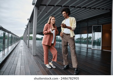 Two colleagues chat on a rooftop terrace, showcasing diversity and inclusion in the modern workplace. - Powered by Shutterstock