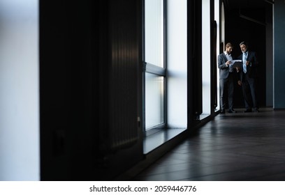 Two colleagues communicating in corridor, partners walking in the modern office - Shutterstock ID 2059446776