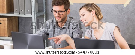 Two colleagues consulting each other's documents on the computers in modern office