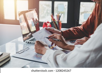 Two Colleagues Discussing Data With Document Data And New Modern Computer Laptop On Desk Table. Close Up Business Team Analysis And Strategy Concept.