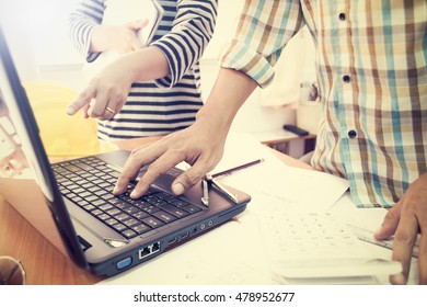 Two colleagues discussing data working with construction plan in office.