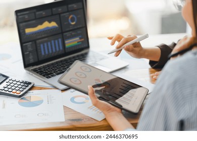 Two colleagues engaged in business analytics, using digital tablets over financial charts. Colleagues Collaborating with Tablets on Business Analytics. - Powered by Shutterstock