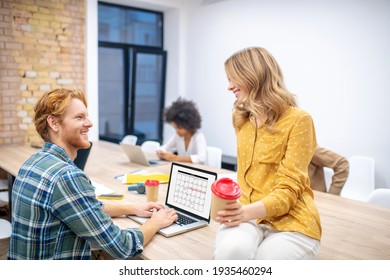 Two colleagues. Ginger guy talking to a blone female colleague in the office