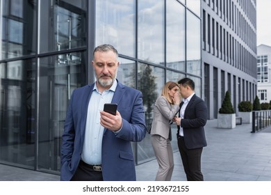 Two colleagues are gossiping at background behind the boss. workmate about bullying problem at work place in office in the break outside Male Coworkers employees man and woman Whispering Behind Back