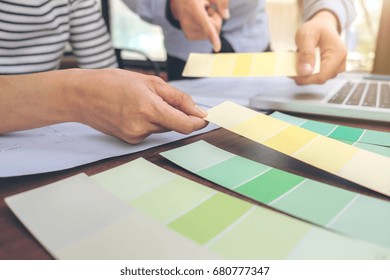 Two colleagues interior Creative creativity graphic designer working with graphics laptop, blueprint and colour chart at workplace on wooden desk , colour ideas style concept.