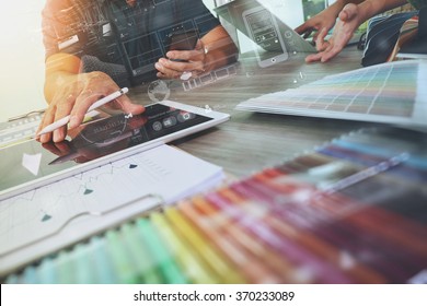 two colleagues interior designer discussing data and digital tablet and computer laptop with sample material and graphics design diagram on wooden desk as concept - Shutterstock ID 370233089