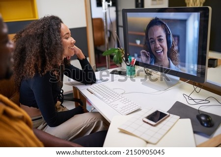 Two colleagues in the office talk to a woman on a conference call