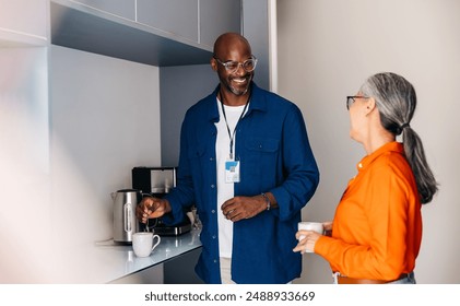 Two colleagues taking a coffee break, relaxing, having a conversation in a modern office kitchen. - Powered by Shutterstock