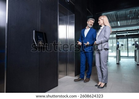 Two colleagues talking while waiting for the elevator in a business center