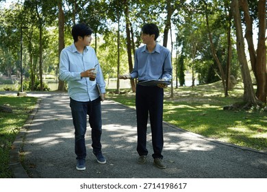 Two Colleagues Talking While Walking in a Park, Outdoor Business Conversation and Collaboration.