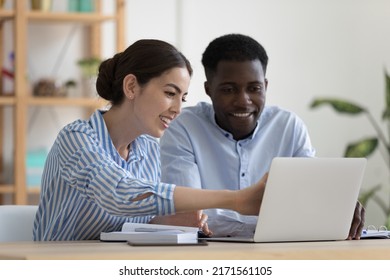 Two Colleagues Use Laptop Discuss Corporate Software. Female Mentor Provide Help Teach African Newcomer Explain Corporate App. Communication, Modern Tech, Client And Saleswoman Meet In Office Concept