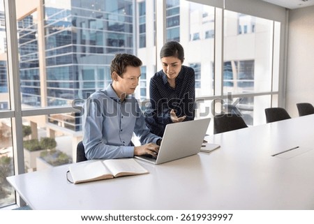 Two colleagues using laptop, preparing report or presentation, analyze received data, researching information, using project management tools to track progress, analyze budgets and revenue. Workflow