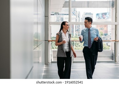 Two colleagues walking and talking in office hall.
Coworkers walking with coffee in modern office building - Powered by Shutterstock