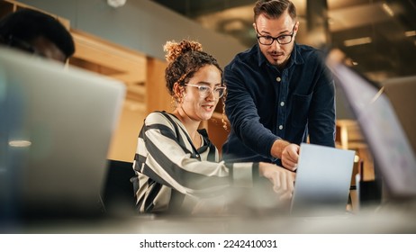 Two Colleagues Working On Laptop in Office. Female Hispanic Help Desk Coordinator Collaborates with White Male Customer Service Agent, They Discuss a Project, Chat, Smile. Teamwork Collaboration - Shutterstock ID 2242410031