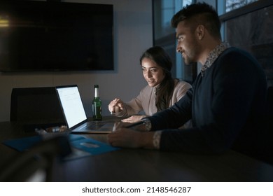 Two colleagues working overtime on laptop in office - Shutterstock ID 2148546287