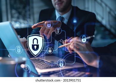 Two colleagues working together to protect clients confidential information and cyber security. IT hologram padlock icons modern office background at night time