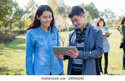Two college student using the Tablet PC on campus lawn