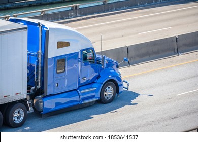 Two color industrial grade diesel big rig semi truck with low cab for best aerodynamics transporting commercial cargo in dry van semi trailer running on the overpass highway road intersection - Shutterstock ID 1853641537