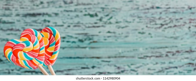 Two colored striped rainbow candy on a stick in the form of a heart. on a blue old vintage wooden background. The concept for Valentine's Day. - Powered by Shutterstock