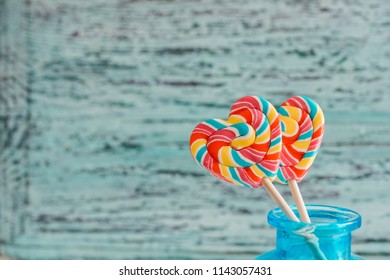 Two colored striped rainbow candy on a stick in the form of a heart. on a blue old vintage wooden background. The concept for Valentine's Day. - Powered by Shutterstock