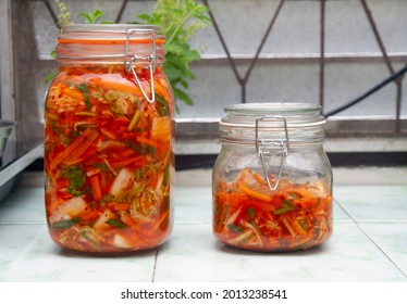 Two colorful glass jars with homemade kimchi vegetable mix on kitchen bench - Shutterstock ID 2013238541