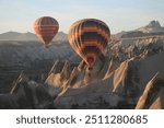 Two colorful hot air balloons flying over Cappadocia at sunrise