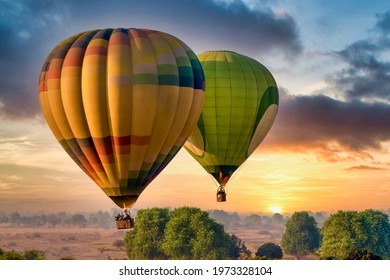 Two colorful hot air balloons filled with tourists float above the landscape at sunrise, part of the annual Pushkar Camel Fair in Rajasthan, India.