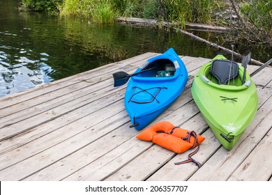 Two Colorful Kayaks And Life Jacket On Dock