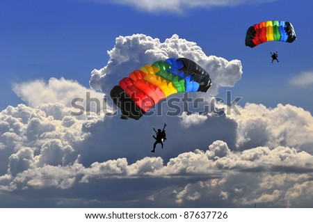 Two colorful parachutes on stormy sky