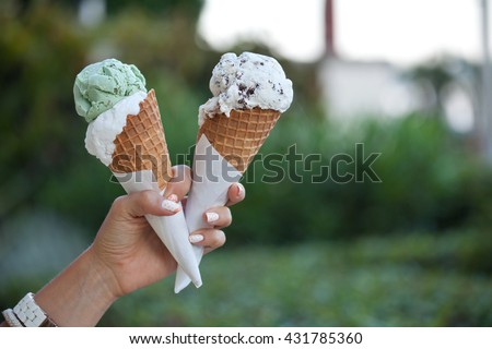 Two colorful tasty ice cream cones in hand. (focus on ice cream)