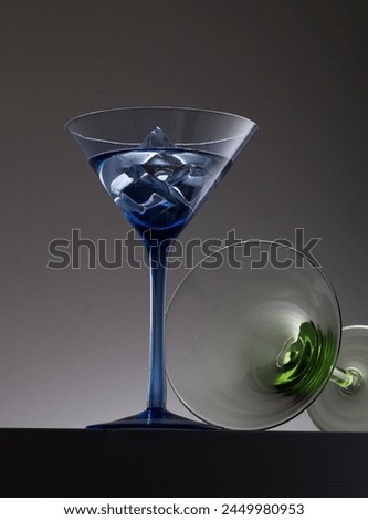 Two coloured cocktail glasses one with vodka and ice