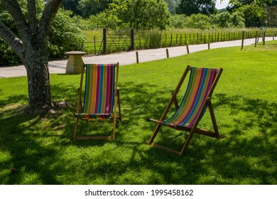 Two Colourful Deck Chairs On A Shady Spot By A Tree In An English Meadow