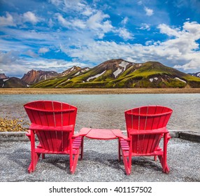 Two comfortable red deck chairs are for rest.  Valley among the rhyolite mountains and shallow streams