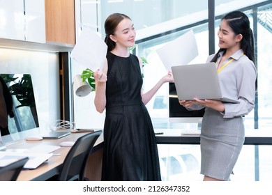 Two Company Employees One Person Holding A Laptop And The Other Holding A Work Document Where The Two Of Them Were Meeting To Discuss The Operation Of The Financial System. 
