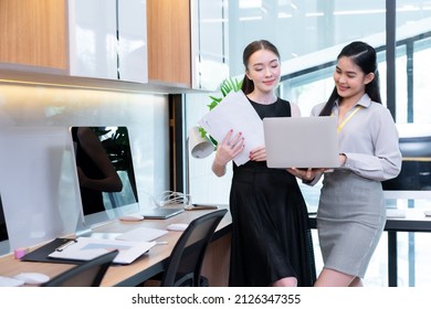 Two Company Employees One Person Holding A Laptop And The Other Holding A Work Document Where The Two Of Them Were Meeting To Discuss The Operation Of The Financial System.