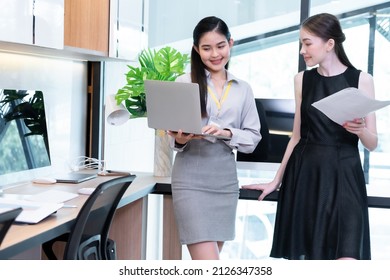 Two Company Employees One Person Holding A Laptop And The Other Holding A Work Document Where The Two Of Them Were Meeting To Discuss The Operation Of The Financial System.