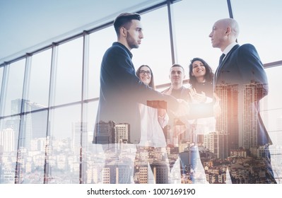 Two confident businessman shaking hands during a meeting in the office, success and partner concept. Double exposition, panorama of modern city. - Shutterstock ID 1007169190