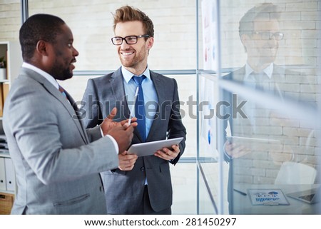 Two confident colleagues sharing ideas at meeting in office