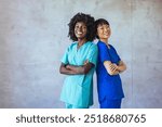 Two confident nurses in colorful scrubs standing back to back in a hospital setting, showcasing teamwork and professionalism. The image represents diversity and healthcare industry dedication.