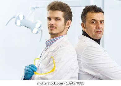 Two Confident Professional Male Dentist Posing Proudly At Their Clinic Back To Back Looking To The Camera Seriously Copyspace Team Teamwork Medicine Medical Clinic Dental Dentistry Stomatology.