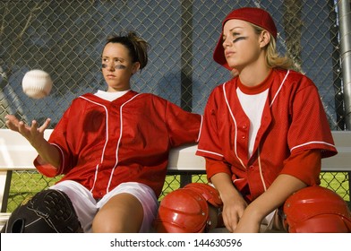 Two confident softball players sitting on the bench in dugout - Powered by Shutterstock