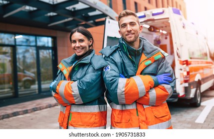 Two confident young doctors looking on the camera on ambulance and hospital background - Powered by Shutterstock