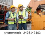 Two construction crane workers in safety vests and helmets using a tablet for planning and communication at a construction site.