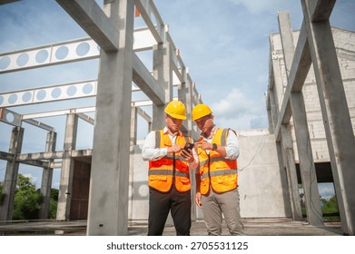 Two construction engineers are discussing project plans over the phone on site.